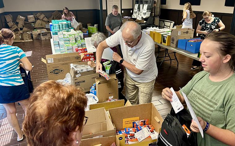 Volunteers loading backpacks with school supplies