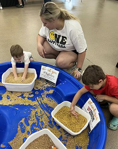 Kids touching bins of soybean, wheat and pasta.