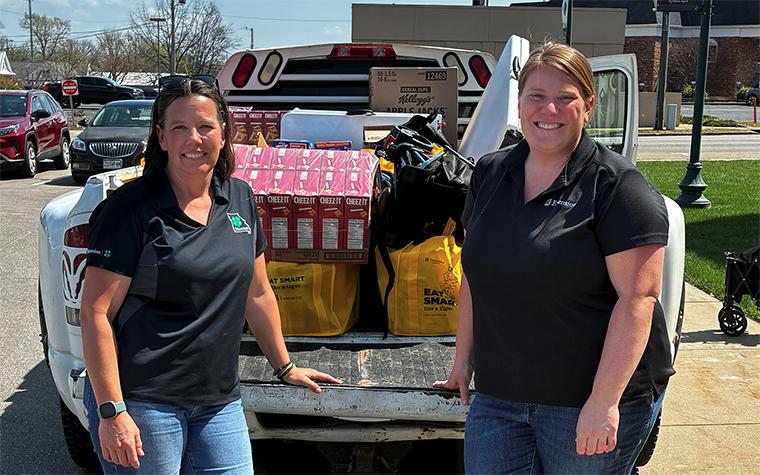 Two women behind a truck loaded with donated food