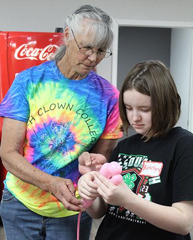 Adult helping girl with balloon animal