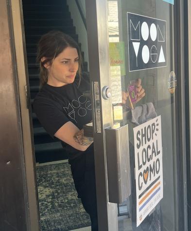 Amber Treece applying RFW decal to front door of Moon Yoga.