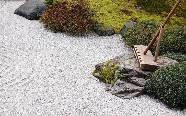 Zen garden with moss, shrubs, gravel and a rake