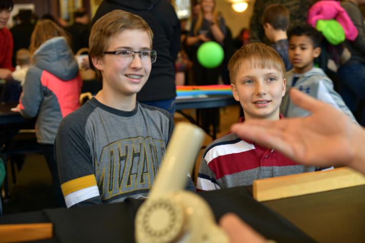 Nathaniel Kauffman, 13, left, and Elijah Kauffman, 10, learn that the ball stays aloft even if the hair dryer is tilted because it floats within a column of faster-moving, lower-pressure air. Photo by Michael Hicks.