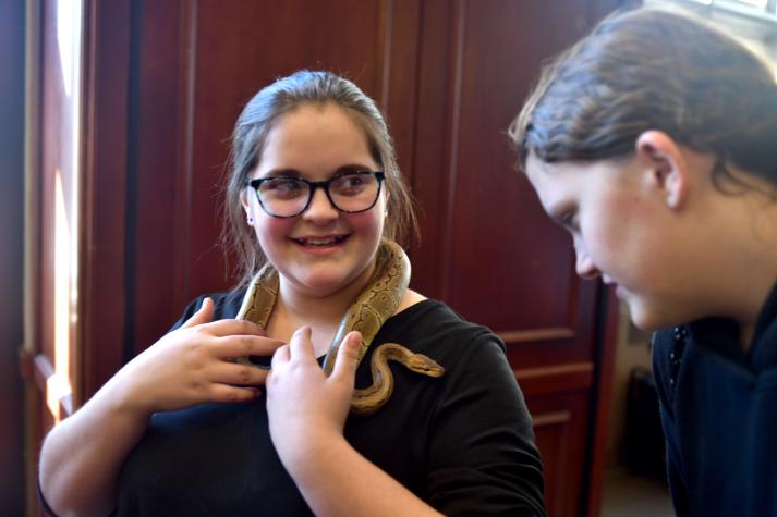 Cali Davis, 13, left, says science is her thing. "I ask a lot of questions at school. Scientists are constantly asking questions.” Her friend, Jordan McManus, 13, eyes the python warily. Photo by Michael Hicks.