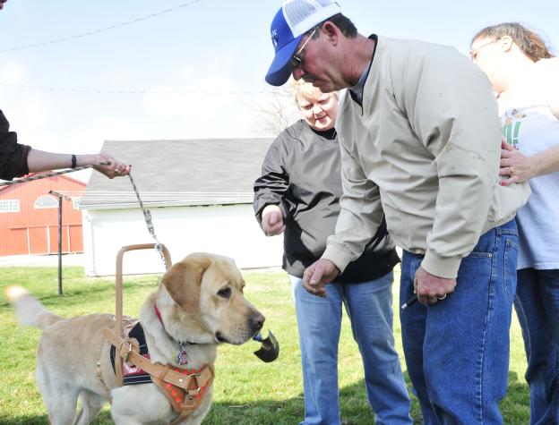 Odie fetches a tool for Bruce Trammell, a Kingston farmer who suffered a brain injury that causes balance and mobility issues. Trammell received the dog from the  PHARM Dog program, part of MU Extension's AgrAbility Project. Roger Meissen/MU Cooperative Media Group 