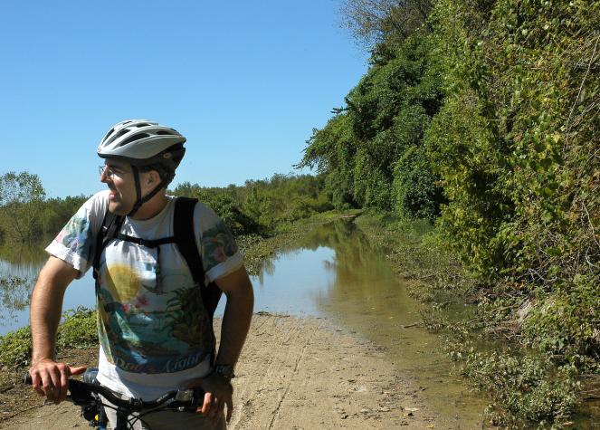Graduate student Bryan Danford, leading the bike trip, stops where flood waters cover the Katy Trail.MU Photo