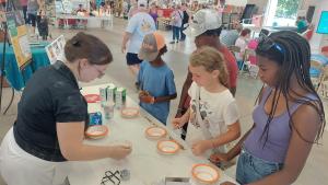 4-H Summer enrichment intern Emma Crocker teaches fairgoers about non-Newtonian fluids, those that can be both solid and liquid, using cornstarch and water.