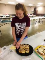 Lincoln County member attaches a fair tag to her cinnamon roll exhibit for the county fair.  Through the breads project, members learn life skills such as how to knead dough and how to select the best type of yeast for their recipe.
