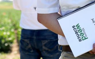 Man holding spiral bound document from MU Weed Science