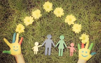 Paper doll family on grass with flowers