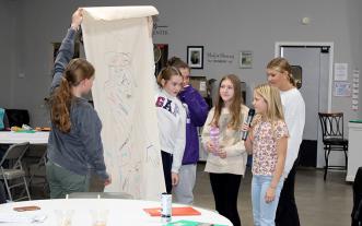 Youths look at life-size human figure drawn on a large piece of paper
