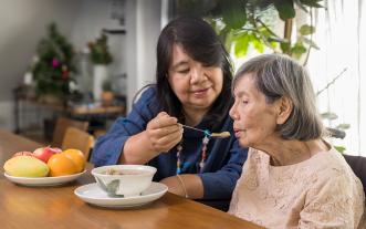 Caregiver feeding elderly woman