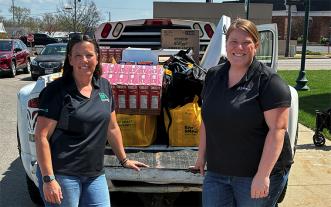Two women behind a truck loaded with donated food