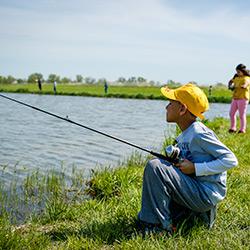 Boy fishing next to a pond