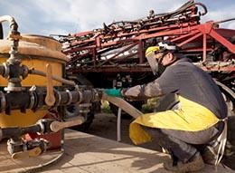 Person working on a pesticide machine with appropriate safety gear on