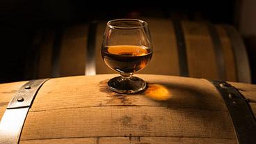 Glass of whiskey sitting on top of barrel