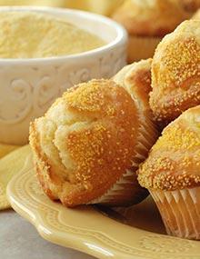 A bowl of cornmeal beside a platter of cornmeal muffins.