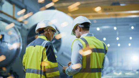 three individuals with hard hats and safety vests in contruction environment