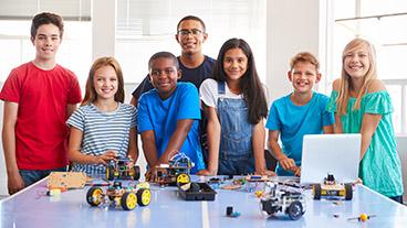 Young teacher and adolescents in robotics club.