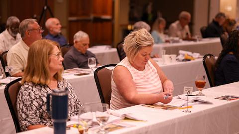 Women sitting at a table at a conference.