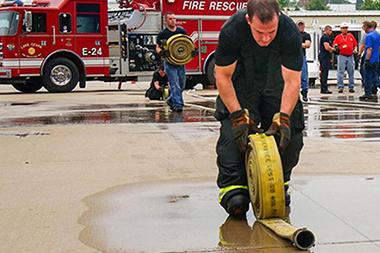 Man rolling up a fire hose.