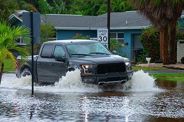 Truck driving on a flooded residential street.
