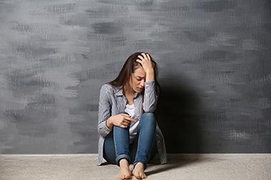 Teenage girl sitting on the floor with her head in her hand