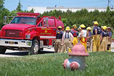 Fire fighters in front of a fire truck and a hydrant.