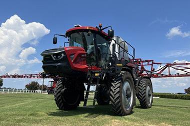 A red spray rig in a field.