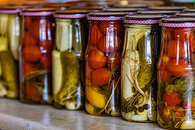 Jars of pickled vegetables lined up on a shelf