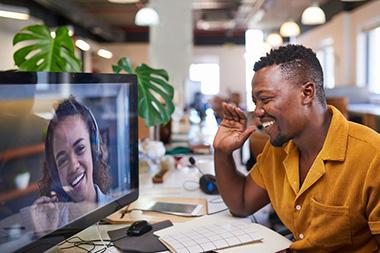 A man talking to a woman on a computer.