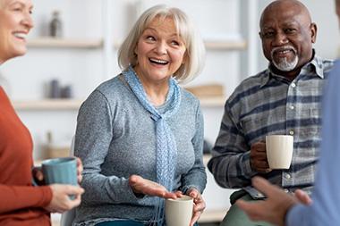 A group of seniors laughing while drinking coffee.