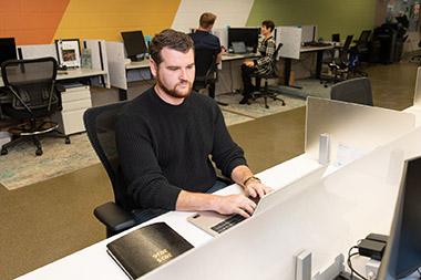 Man typing on a laptop in a computer lab