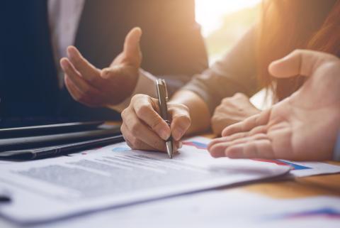 Two hands signing loan documents