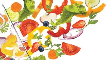 Fresh fruits and vegetables flying out of a clear glass bowl.