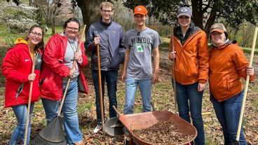 college students raking leaves