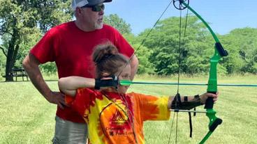 girl shooting arrow with instructor