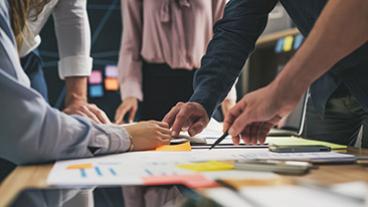 Team of people gathered around conference table working on documents together