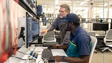 man showing another man computer skills