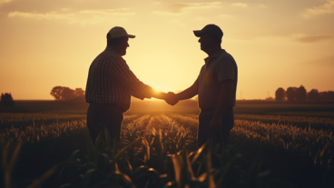 two farmers in a field shaking hands