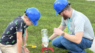 Man and boy launching small rocket made of a water bottle and fins