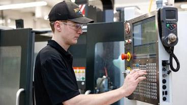 Man in factory using control panel on machinery.