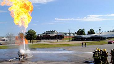 Fire fighters spring a burning gas tank with water.