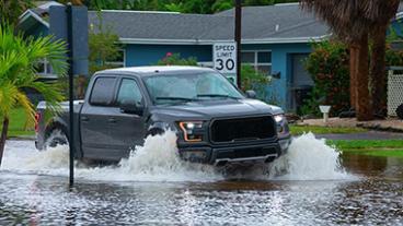 Truck driving on a flooded residential street.