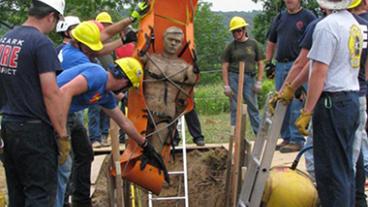 Fire fighters pulling a dummy out of a trench during training.