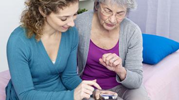 Woman showing a senior citizen how to use a smartphone