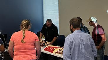 Class with an instructor teaching participants the difference cuts of meat on a cow