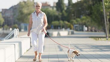 A senior woman walking with her dog