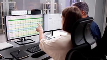 A woman pointing out data on an excel spreadsheet to a man