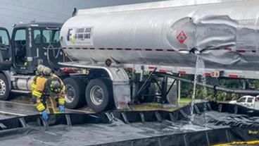 Gasoline tank truck with a fire fighter containing a spill.